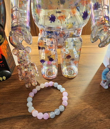 this bracelet features a blend of amethyst, aquamarine, and rose quartz gemstones. Designed to fit a 15cm wrist, it is tied together with an elastic string for a comfortable and secure fit. Amethyst promotes tranquility, aquamarine brings clarity, and rose quartz symbolizes love. The 